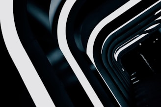 Curved architectural elements feature prominently, with alternating light and dark bands creating a futuristic tunnel effect. The space is lit from above by seamless, glowing strips that enhance its clean, sleek lines and modern aesthetic.