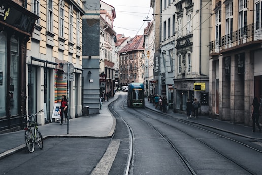 a narrow city street with a train on the tracks