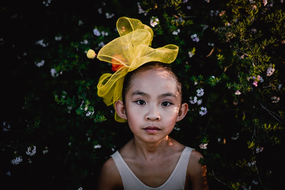 photo of girl wearing white top leaning on plant