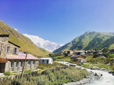 Charming stone cottages nestled in lush green Albanian mountains under a clear blue sky.