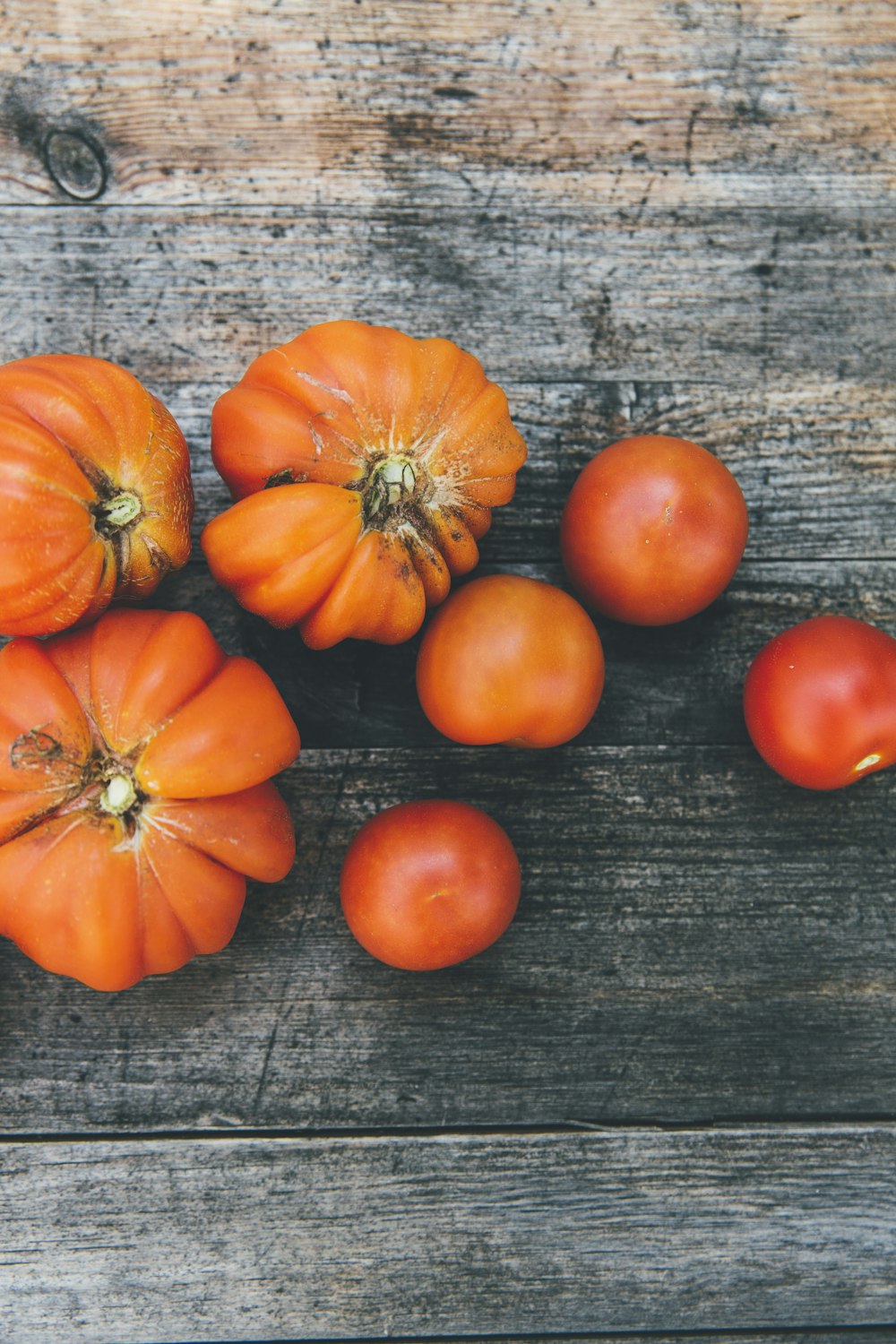 vier rote Tomaten und drei orangefarbene Früchte
