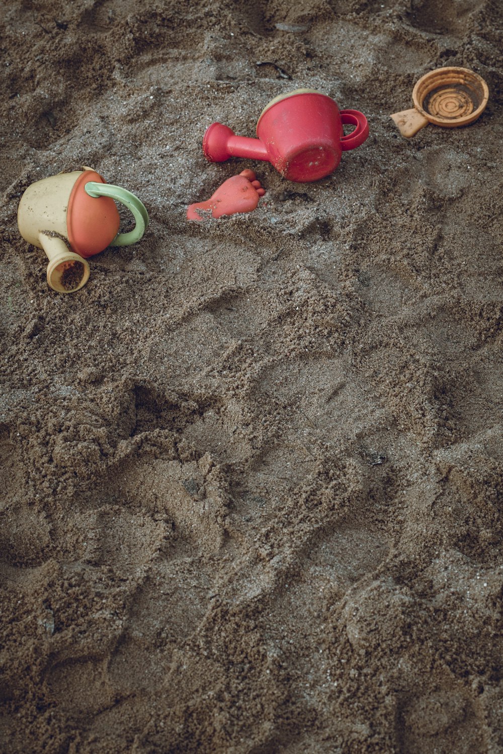 two yellow and red plastic watering cans on seashore