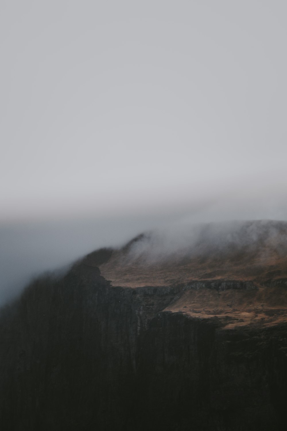 a mountain covered in fog and clouds on a cloudy day