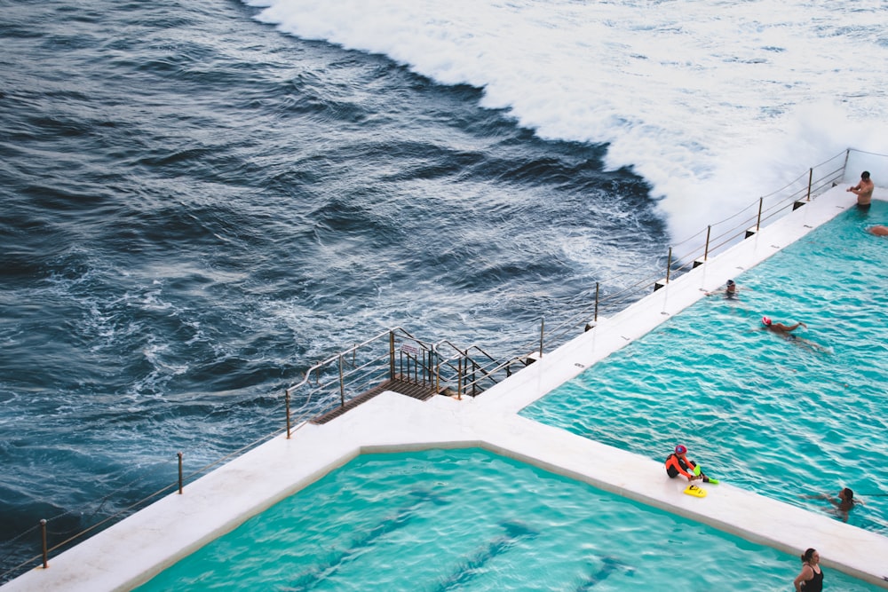 people swimming in pool near sea during daytime