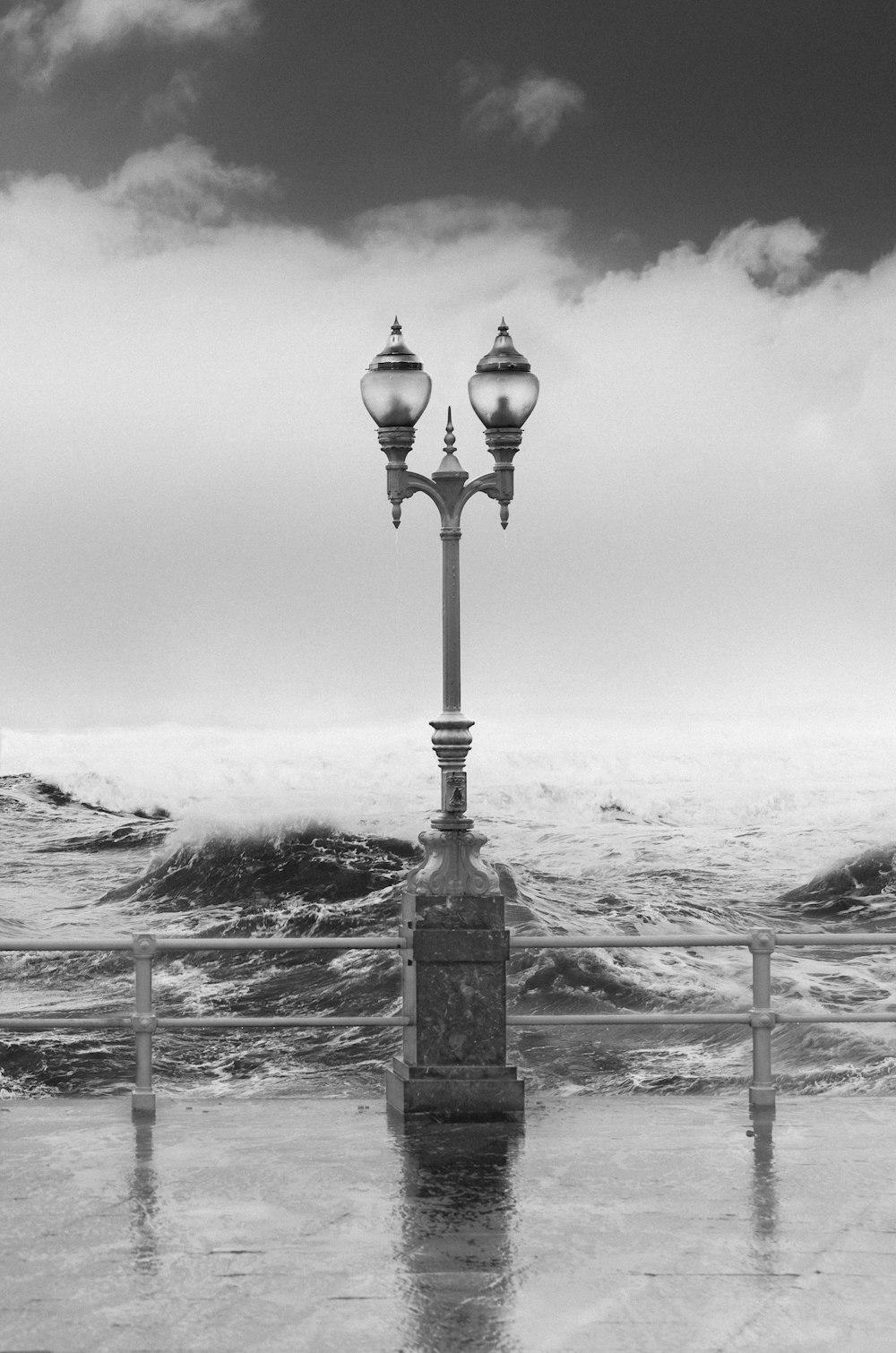 grayscale photography of outdoor lamp near sea