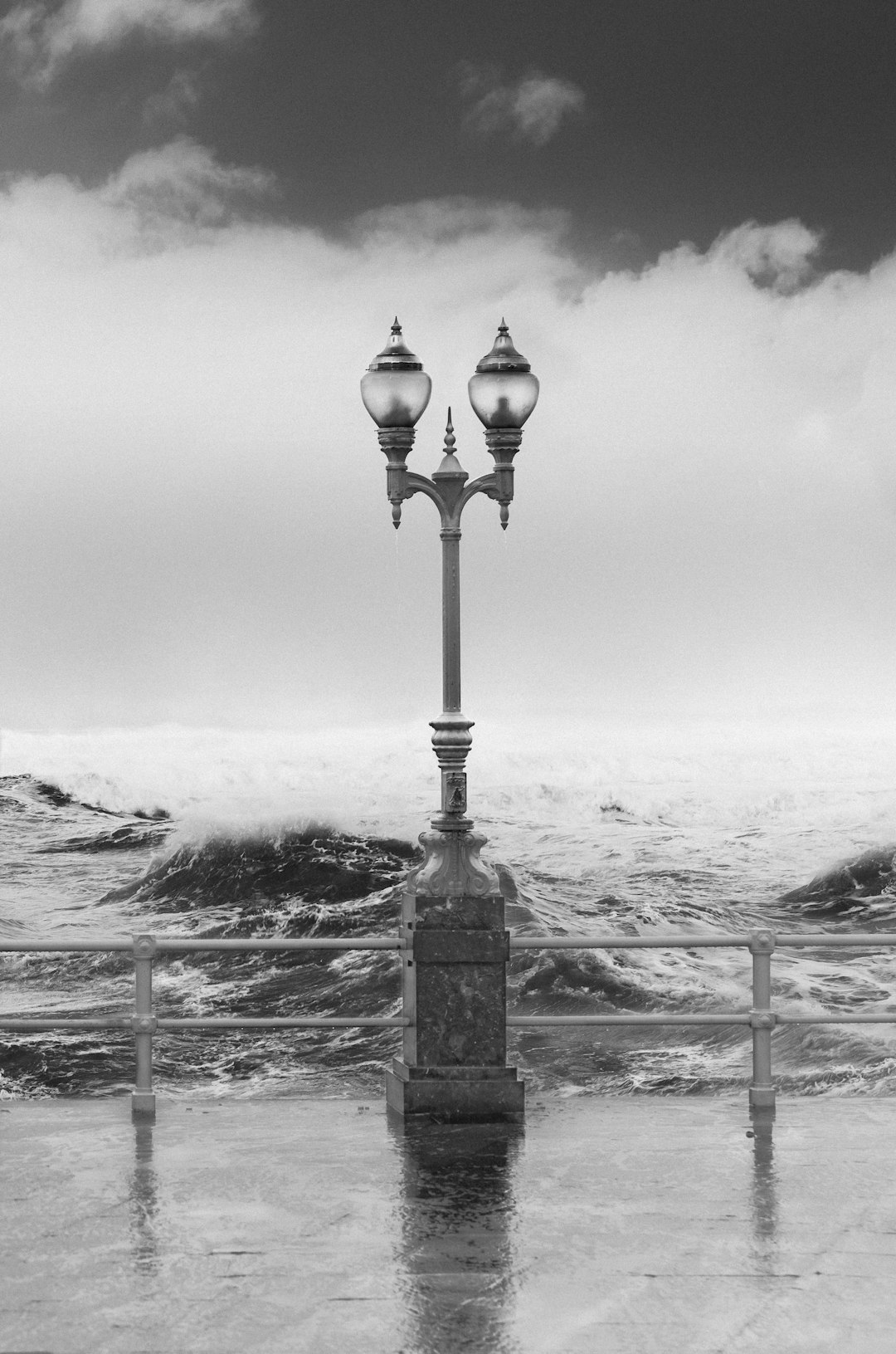 grayscale photography of outdoor lamp near sea