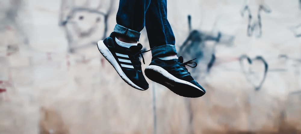 person showing pair of black-and-blue adidas running shoes