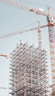 gray metal building frame near tower crane during daytime