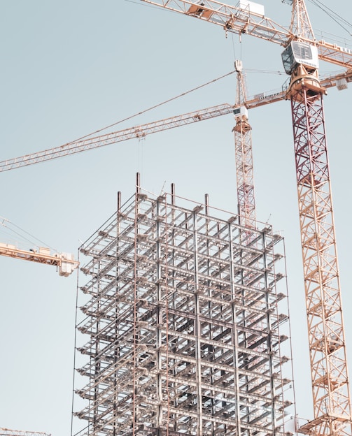 gray metal building frame near tower crane during daytime