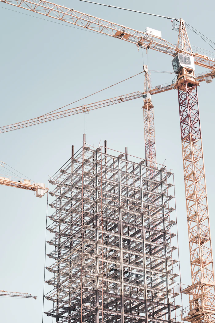 A steel building frame under construction beside a tower crane
