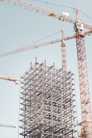 Structural steel frame rising next to a tower crane, similar to the roof truss arch work underway at the Athletics ballpark