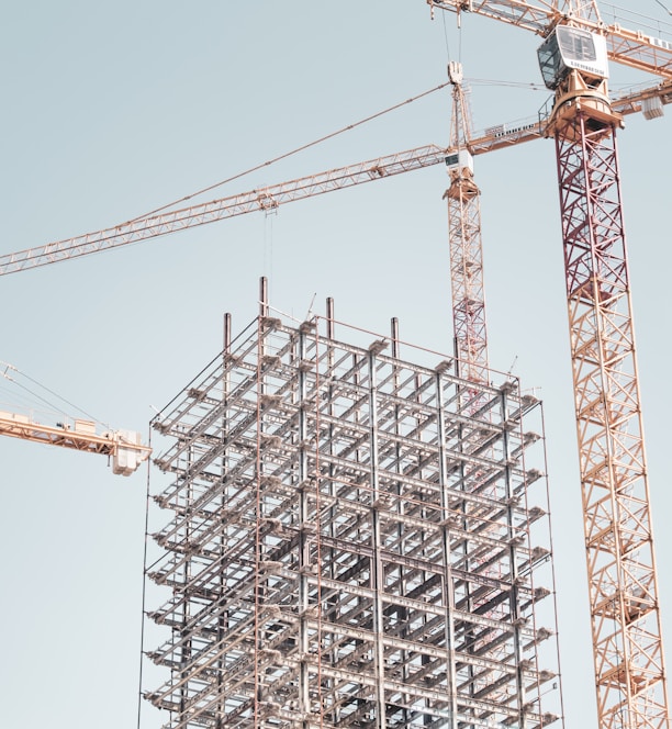 gray metal building frame near tower crane during daytime