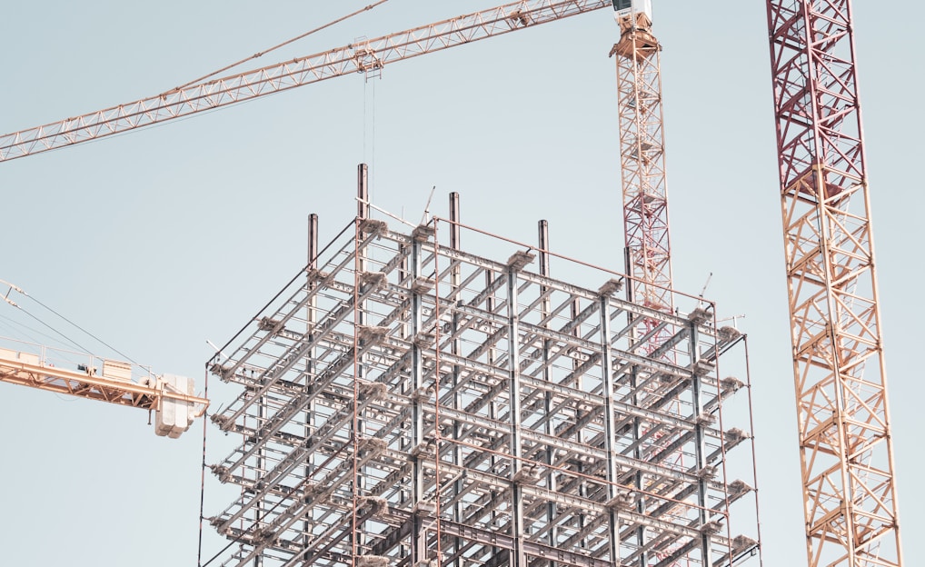 gray metal building frame near tower crane during daytime