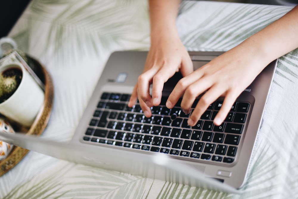 person's hand on keyboards laptop