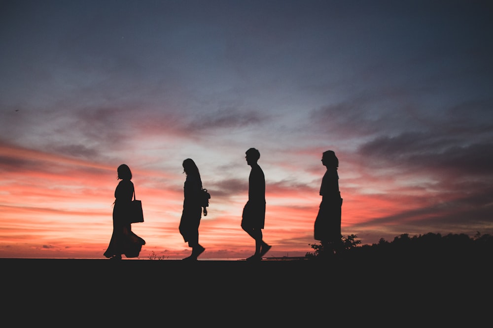 silhouette of four person walking on ground