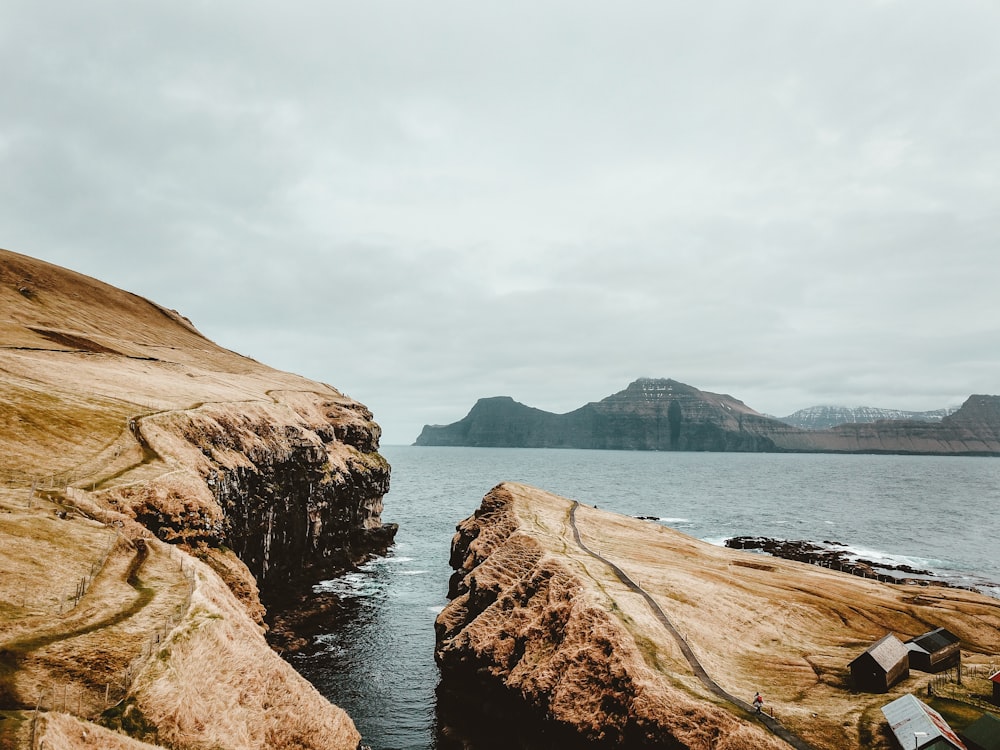 brown rock formation near body of water under blue sky