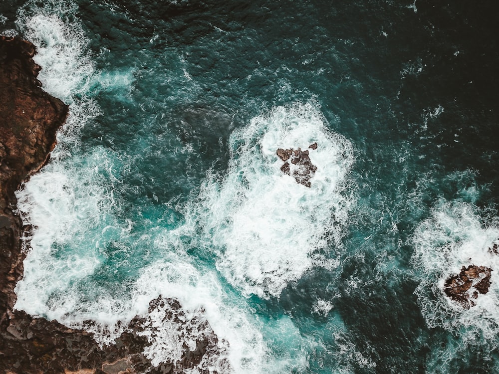 aerial photo of crashing waves through rocks