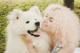 A happy pet parent hugging their dog dressed in a cute, handcrafted dress outdoors