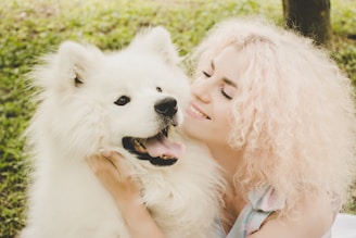 A happy pet owner holding a freshly groomed dog, smiling in a bright outdoor setting.