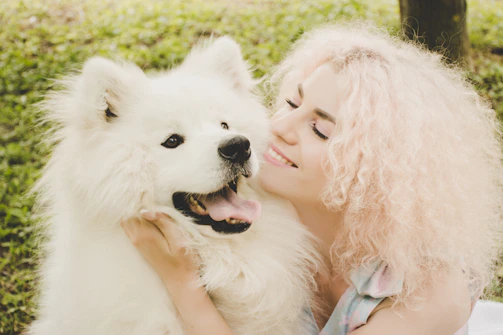 A cheerful pet parent happily chatting on their phone with their dog beside them.