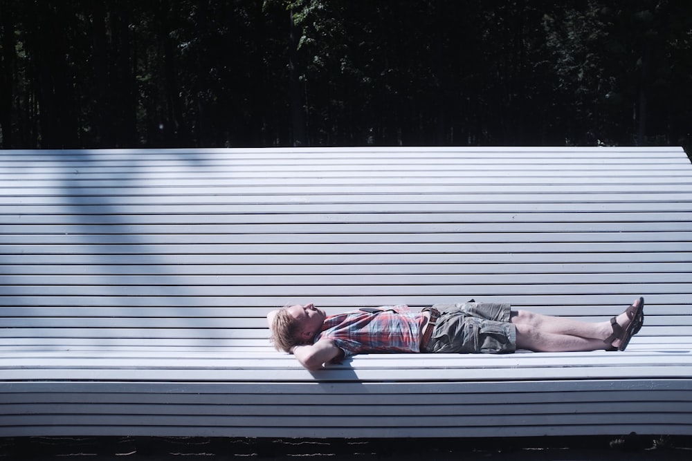 man lying on bench during daytime