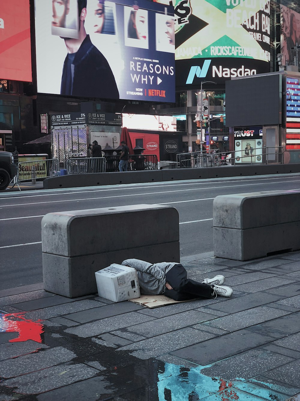 pessoa deitada no chão de concreto ao lado da estrada de asfalto
