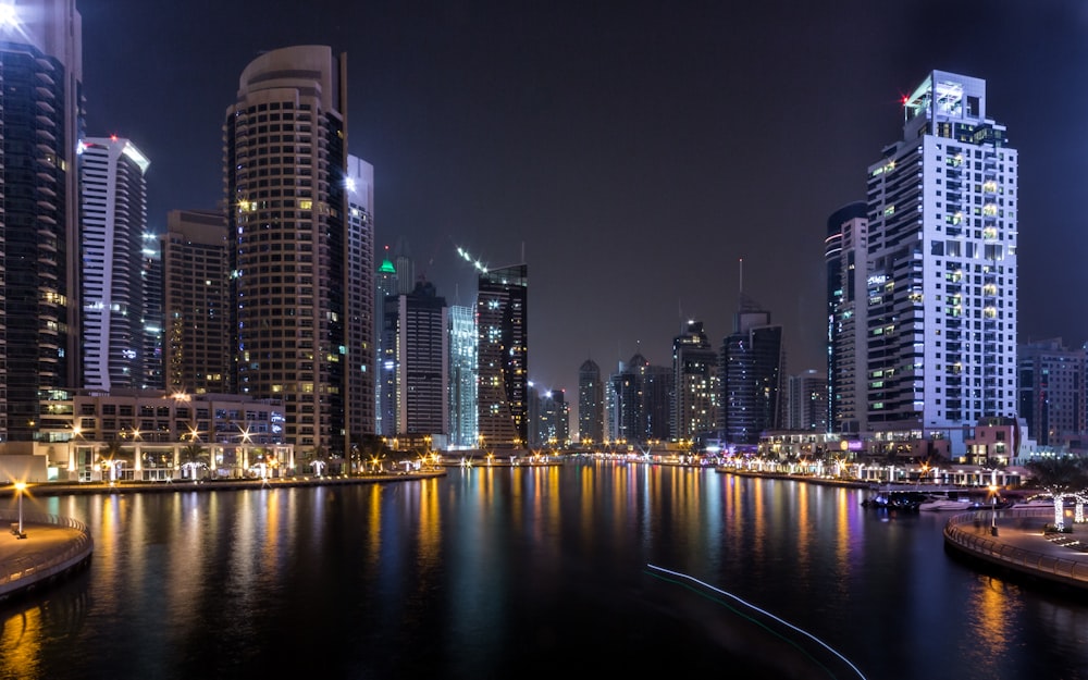 edifícios iluminados da cidade ao lado do corpo de água