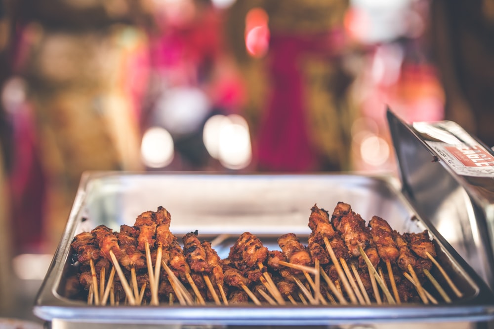 selective focus photography of skewered pork on tray