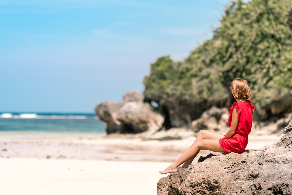 암석 형성 해변에 앉아있는 여자의 선택적 초점 사진