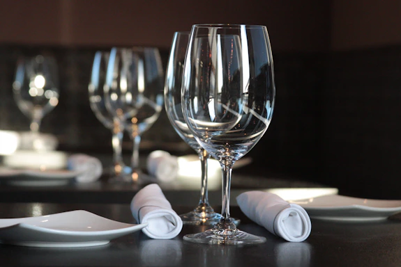 Elegant close-up of a gold-accented reservation book resting on a dark navy tablecloth under warm ambient lighting.