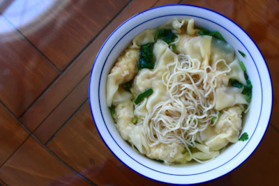 A steaming bowl of authentic Chinese noodles garnished with fresh herbs.