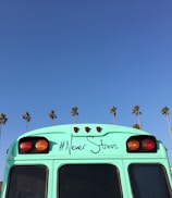 low-angle view of blue bus near coconut palm trees