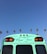 A turquoise bus with #NeverStress written on the back combines with the clear blue sky. Tall palm trees are seen in the background, suggesting a tropical or Californian setting.