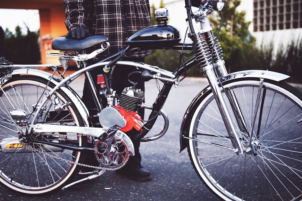 Persona che tiene in mano una bicicletta motorizzata nera