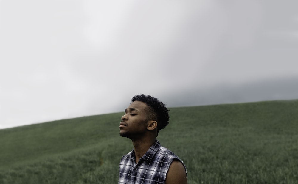 man wearing black, gray, and white plaid sleeveless top