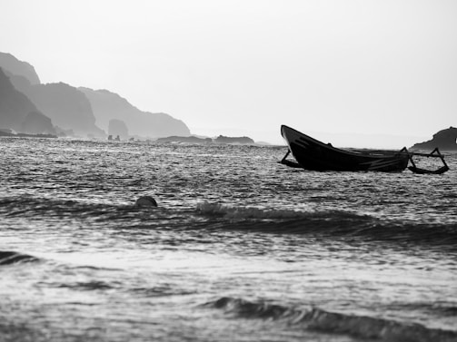 A darkroom print by Somerled featuring an old wooden boat moored on a calm shore, evoking stillness.
