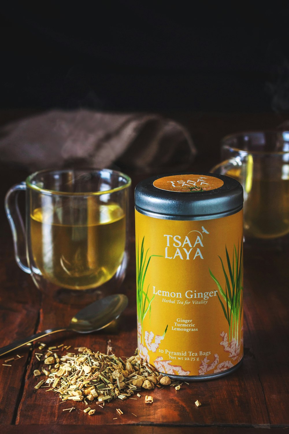 clear glass mug and Tsaa Laya lemon ginger labeled container on brown wooden table