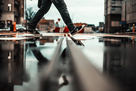 person walking in wet road in Poznań Poland