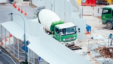 green and white mixer truck at the construction site