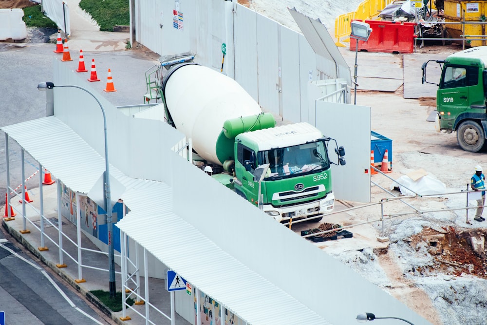 green and white mixer truck at the construction site