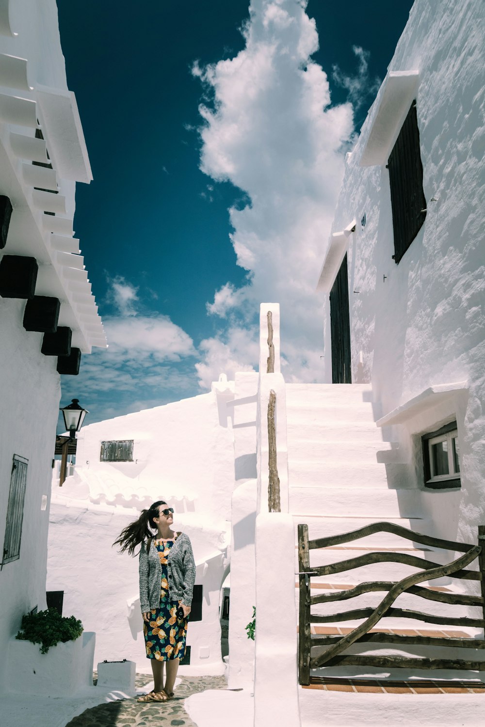 Femme debout près d’un bâtiment blanc et d’escaliers