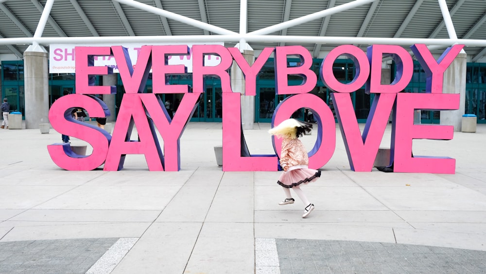 Una ragazza sta correndo davanti a un cartello che dice che tutti dicono amore