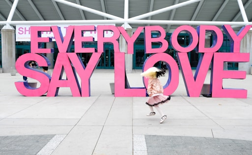 a girl is running in front of a sign that says everybody say love