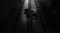 A dimly lit industrial setting with two cables running vertically along a textured floor. There are mechanical components in the center, casting shadows due to the minimal lighting.