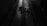 A dimly lit industrial setting with two cables running vertically along a textured floor. There are mechanical components in the center, casting shadows due to the minimal lighting.