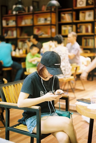 Young people engaging with news on smartphones in a cozy café setting.