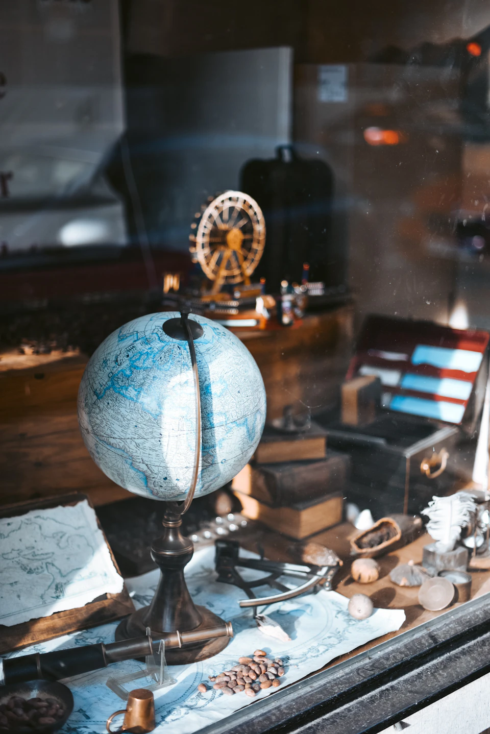 Antique globe dominates window display with miniature Ferris wheel and various trinkets nearby