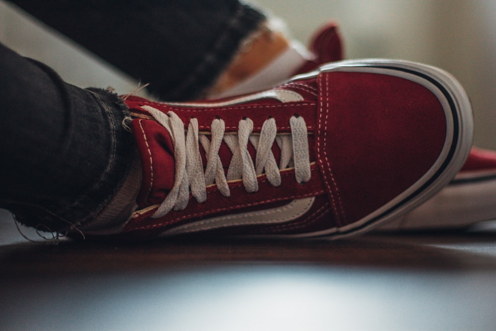 a person's feet with red shoes and white laces