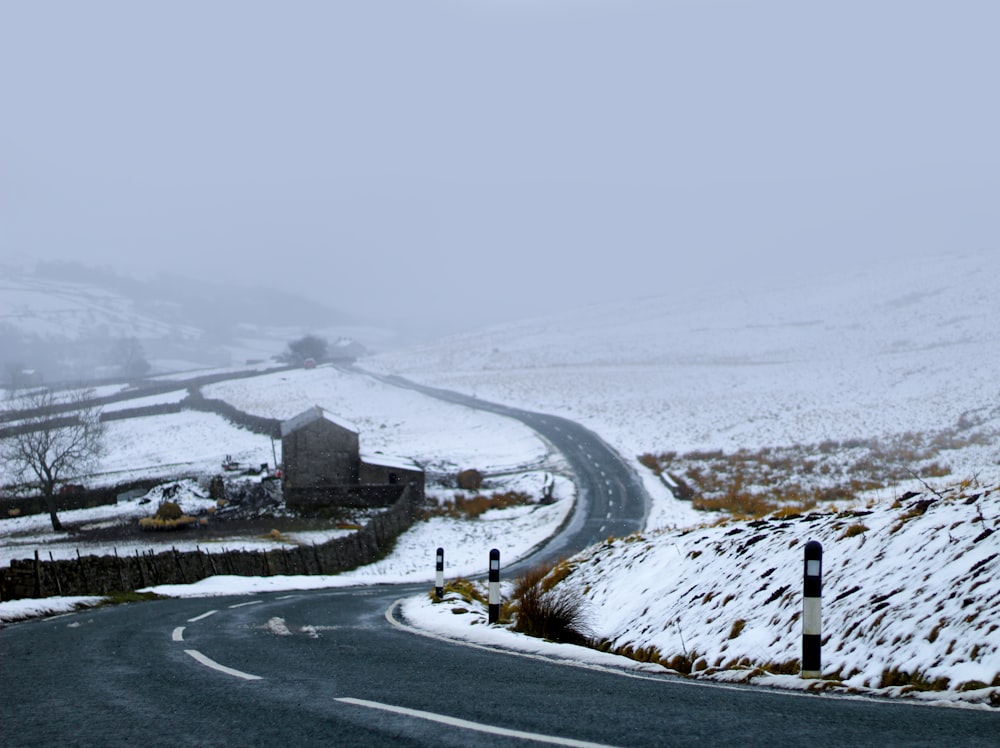 asphalt road between snow-covered field during daytime