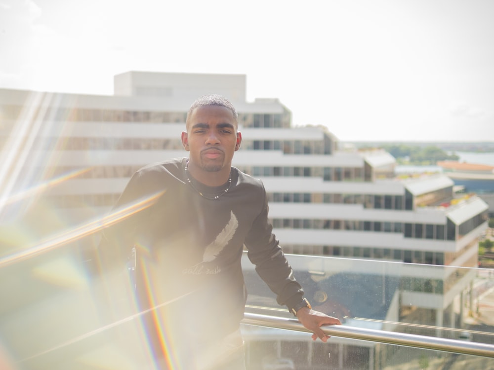 man in black long-sleeved shirt standing near glass handrails